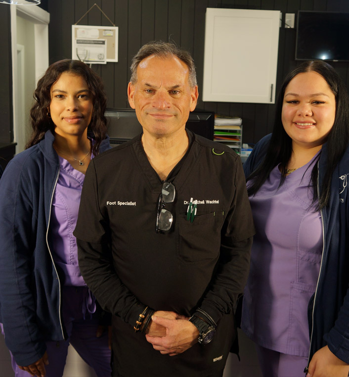 Dr. Mitchell Wachel and a couple of his podiatry specialists are smiling at the camera.